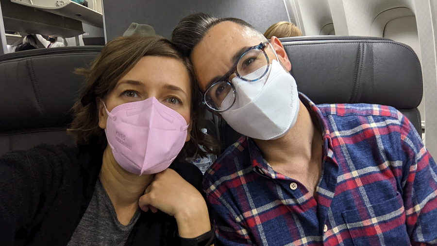 The author and Rand taking a selfie on a plane; both of them are wearing masks. 